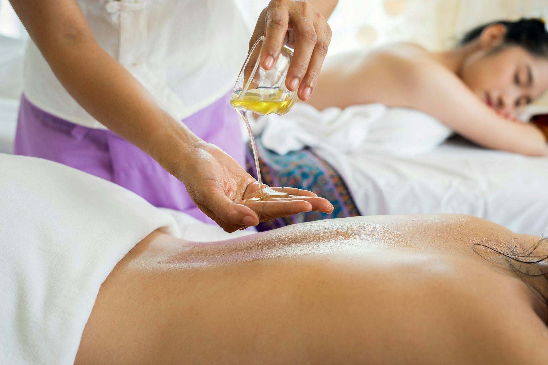 Therapist pouring warm massage oil before a Swedish massage
